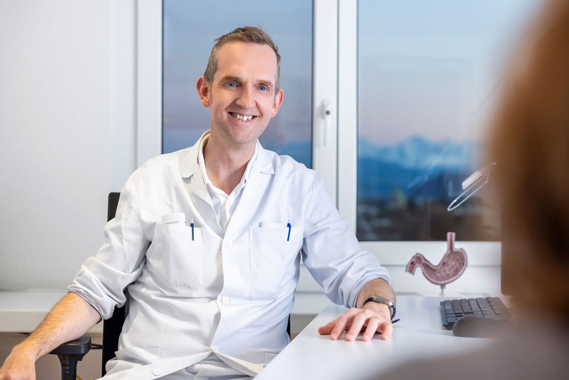 Dr. med. Christoph Matter im Gespräch mit Patientin, Beratung zu Magen-Darm-Erkrankungen, medizinische Untersuchung, Facharzt für Gastroenterologie, Gesundheitsvorsorge, medizinische Beratung.