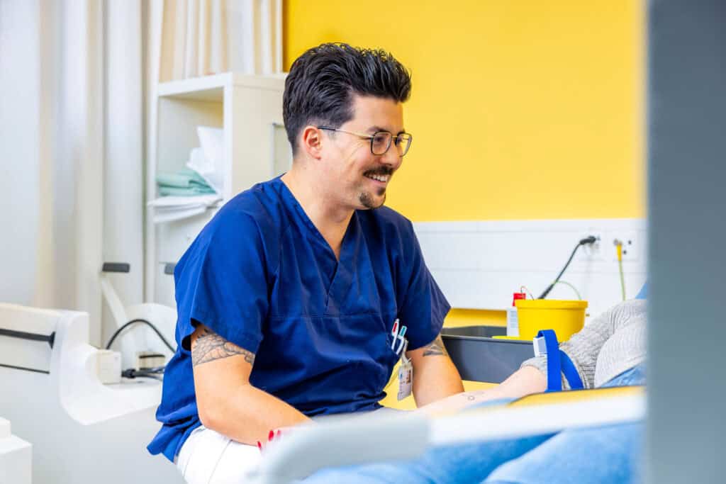 Arzt in blauer Klinikuniform bei Beratung im Crohn-Colitis-Zentrum, das spezialisierte Behandlung für entzündliche Darmerkrankungen wie Crohn und Colitis bietet.